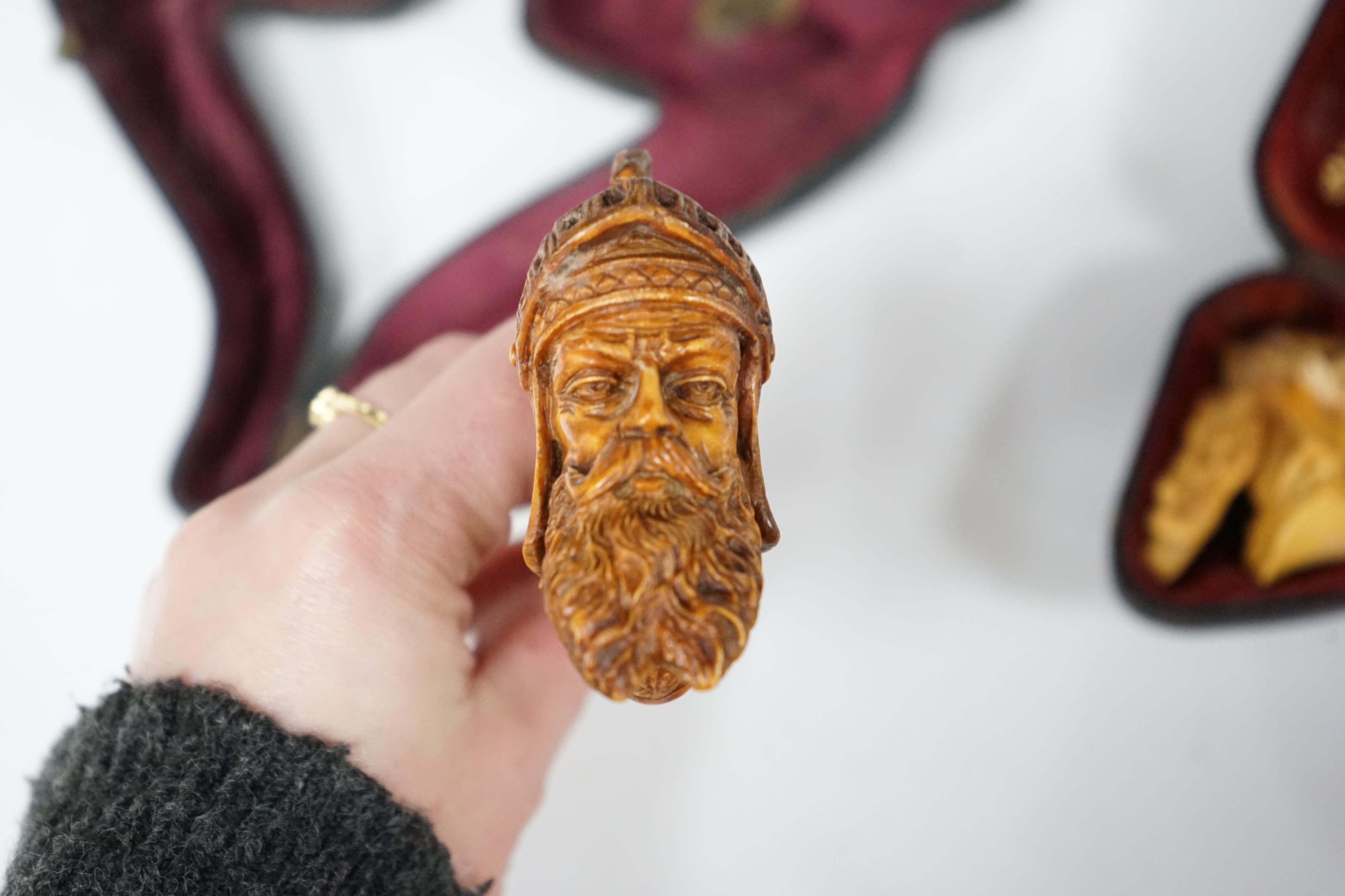 Two cased novelty Meerschaum pipes, their bowls modelled as an Arthurian knight and another a bearded man, both with amber mouthpieces, largest 16cm long